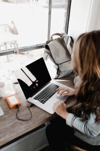 girl wearing grey long-sleeved shirt using macbook