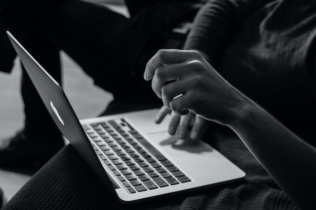 grey photo of person using macbook