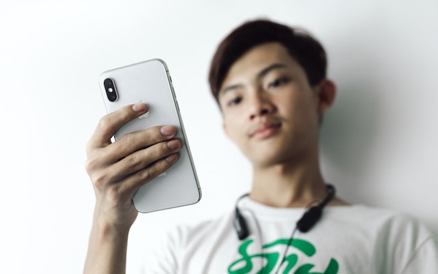 man in white crew neck shirt holding iphone