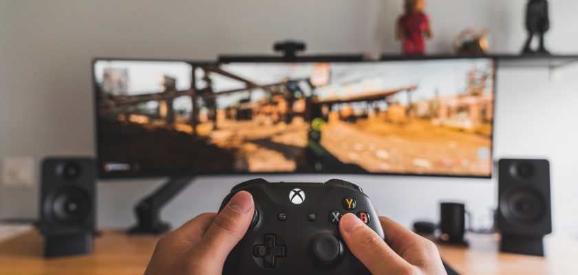 person holding xbox gamepad in front of monitor