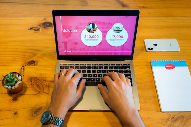 person using macbook on brown wooden table