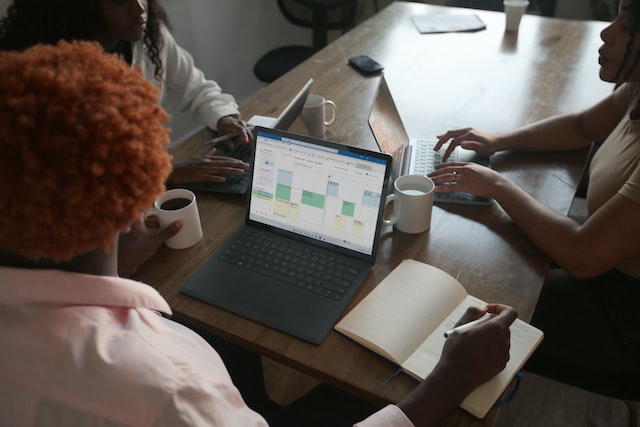 three people in a meeting at a table discussing schedule